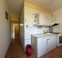 A kitchenette with white cabinets and a stove in a 2-room apartment.