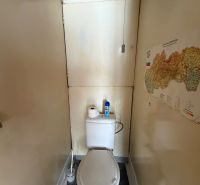 A narrow toilet with a map on the wall in a 3-room apartment.