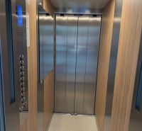 An elevator with a wooden decor floor and metal walls.