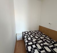 A simple room in a 3-room apartment with a bed and a wooden decor floor.