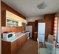 A kitchen in a 3-room apartment with white cabinets and a floor with a wood decor.