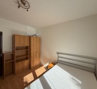 A bedroom in a 3-room apartment with white walls and a floor with a wood decor.