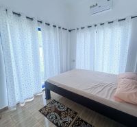 Bedroom in a family house with a bed, curtains, and a wooden decor floor.