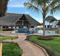 A family house in Zanzibar with a swimming pool and a palm tree in the garden.