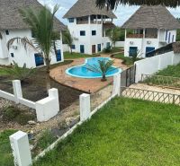Family houses in Zanzibar with a pool, palm trees, and a lawn create a tropical atmosphere.