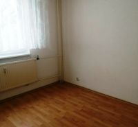 A room in a 3-room apartment with a wooden-patterned floor, curtain, and radiator.