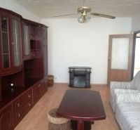 Living room with wood-patterned flooring, a wardrobe, and a sofa in a three-room apartment.