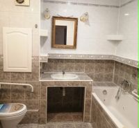 A bathroom in a 3-room apartment with a bathtub, mirror, and toilet, tiled.