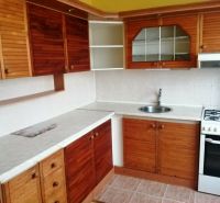A kitchen in a 3-room apartment with wooden cabinets and a white countertop.