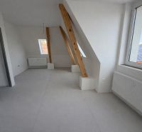 Attic interior in a 2-room apartment with bright walls and beams.