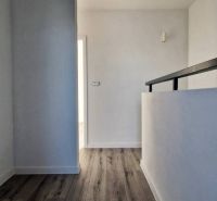 A hallway in a family house with a wooden decor floor and white walls.