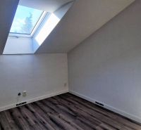 Attic room with a large skylight and wooden decor flooring in a family house.