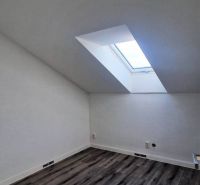 Attic room with a wooden decor floor and a skylight in a family house.
