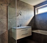 A bathroom with a shower and a bathtub in a 4-room apartment.