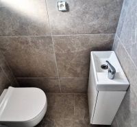 Toilet with a sink in a family house, gray wall tiles.