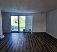 A room in a family house, large windows, white walls, wooden decor flooring.