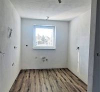 A view into a room of a family house with a wooden decor floor and a window.