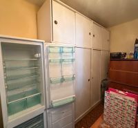 An open refrigerator and built-in wardrobes in the room of a 2-room apartment.