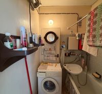 A bathroom in a 2-room apartment with a shower, sink, and washing machine.