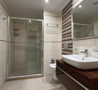 Bathroom with a shower, sink, and cabinets with a wooden decor on Unique Properties.