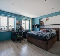 Bedroom in a family house, blue walls, bed, desk, and floor with wooden decor.