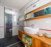 A bathroom with a spacious shower and a wooden cabinet in a family house.
