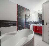 A bathroom in a family house with a bathtub, a red cabinet, and a silver radiator.