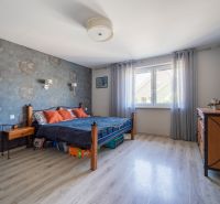 A bedroom in a family house with a wooden decor floor, wallpaper, and solid wood furniture.