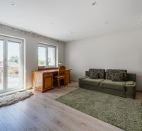 Living room in a family house with wood-patterned flooring, a sofa, and a desk.