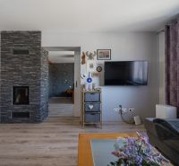 Interior of a family house with a television, decorations, and a wooden-patterned floor.