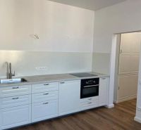 A kitchen in a 3-room apartment with white cabinets and a wood-patterned floor.
