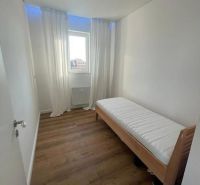 A narrow room with a bed and a wooden floor decor in a 3-room apartment.