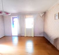 A room in a family house with a wooden decor floor, a floral chandelier, and a painting on the wall.