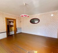 A room in a family house with a wooden decor floor and patterned walls.