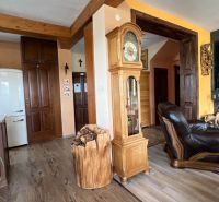 Interior of a villa with wooden decor flooring, antique clock, and fireplace.