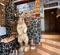 Interior of a villa with wooden animal sculptures and stone walls.
