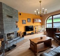 Living room in a villa with a fireplace, wooden decor flooring, and leather furniture.