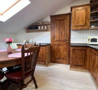 A kitchen in a villa with wooden cabinets, a dining table, and a floor with a wooden decor.