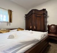Bedroom in the villa with a cabinet, chair, bed, and golden pillows.