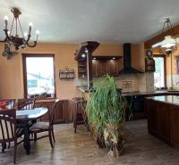 Wooden furniture in the kitchen with a wood-patterned floor and a large window.