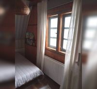 A room in a family house with dark wood paneling and a bed by the window.