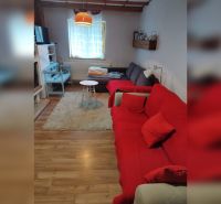 Living room in a family house with a wooden decor floor and a red sofa.