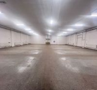 Spacious interior of warehouses and halls with ceiling lighting and tiled flooring.