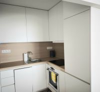 A kitchen with white cabinets and a stainless steel sink in a two-room apartment.