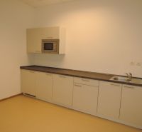 A kitchen unit with a built-in microwave and sink in the office.
