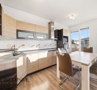 A kitchen in a 3-room apartment with a wooden decor floor and a dining table.