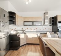 A kitchen in a 3-room apartment with a wooden decor floor and light furniture.