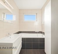 Bathroom in a 3-room apartment with a bathtub, sink, and light tiles.