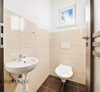 A bathroom in a 3-room apartment with a toilet, sink, and window.