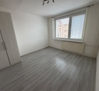 A room in a one-room apartment with a wooden decor floor and white walls.